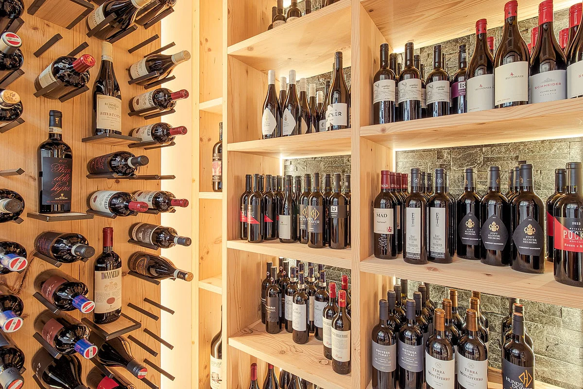A well-stocked wooden wine rack in a wine cellar with bottles featuring various labels