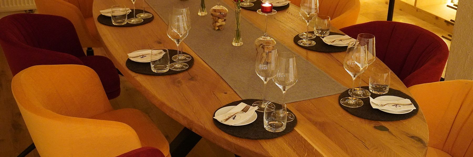 Gedeckter Holztisch im Weinkeller mit Kerzenlicht und eleganter Gläser-Dekoration