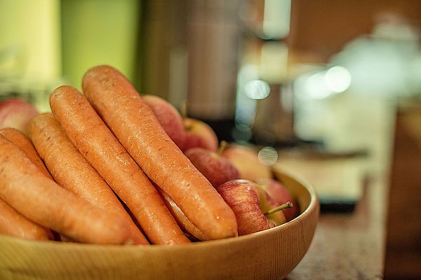 Frische Karotten und Äpfel in einer Holzschale auf einem Buffet