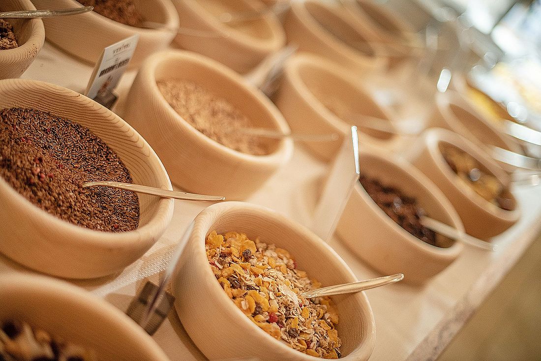Auswahl an Müsli und Körnern in Holzschalen am Frühstücksbuffet