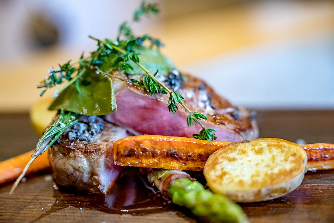 Medium gebratenes Steak mit Gemüse, frischen Kräutern und Sauce kunstvoll angerichtet