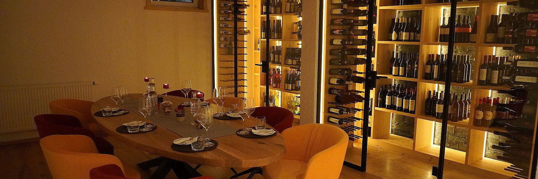 Weinkeller mit großem Holztisch, Gläsern und stilvoller Beleuchtung