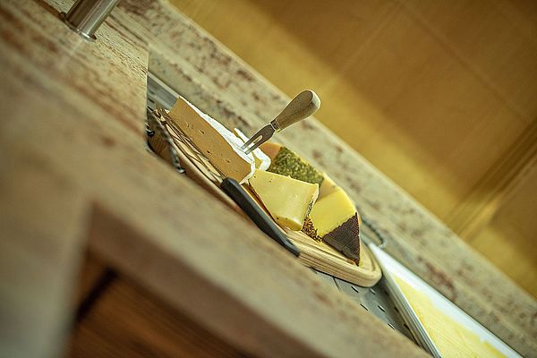 Verschiedene Käsesorten auf einem Holzbrett mit Käsemesser am Buffet