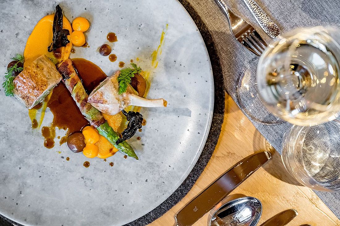 Raffiniert angerichtetes Lammgericht mit Spargel, Karottenpüree und Jus auf edlem Keramikteller