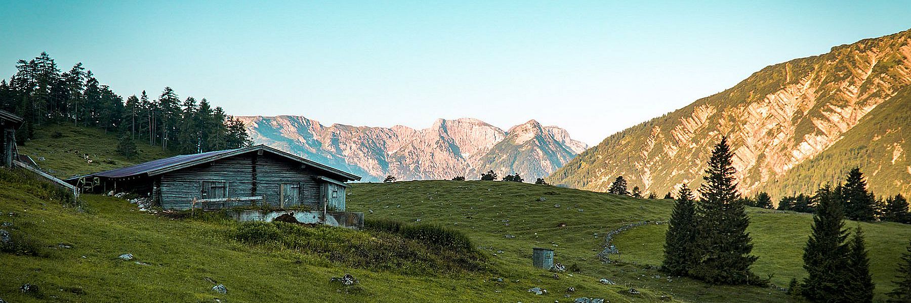 Alte Alm auf einer Hütte in den Bergen in Sommer mit wolkenlosem Himmel