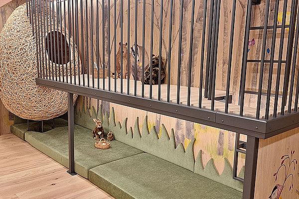 Kinderspielecke mit Hängesessel, Waldmotiven, Plüschtieren und grün gepolsterter Sitzecke