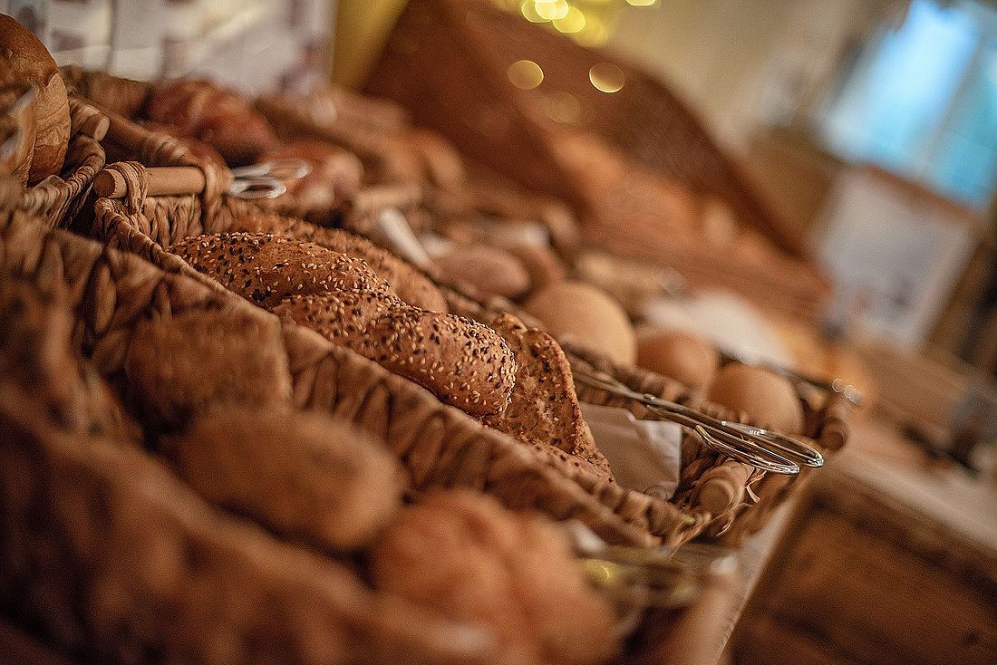 Frisch gebackene Brötchen in rustikalen Körben am Frühstücksbuffet